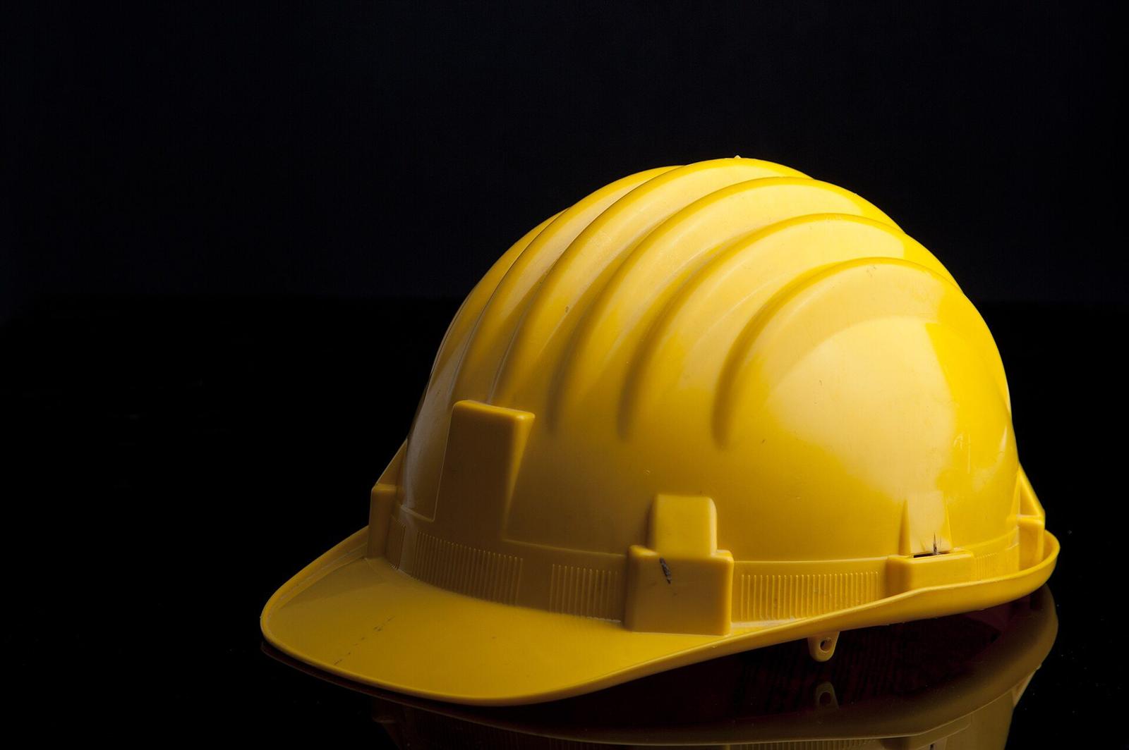 A yellow protective hard hat photographed against a dark background